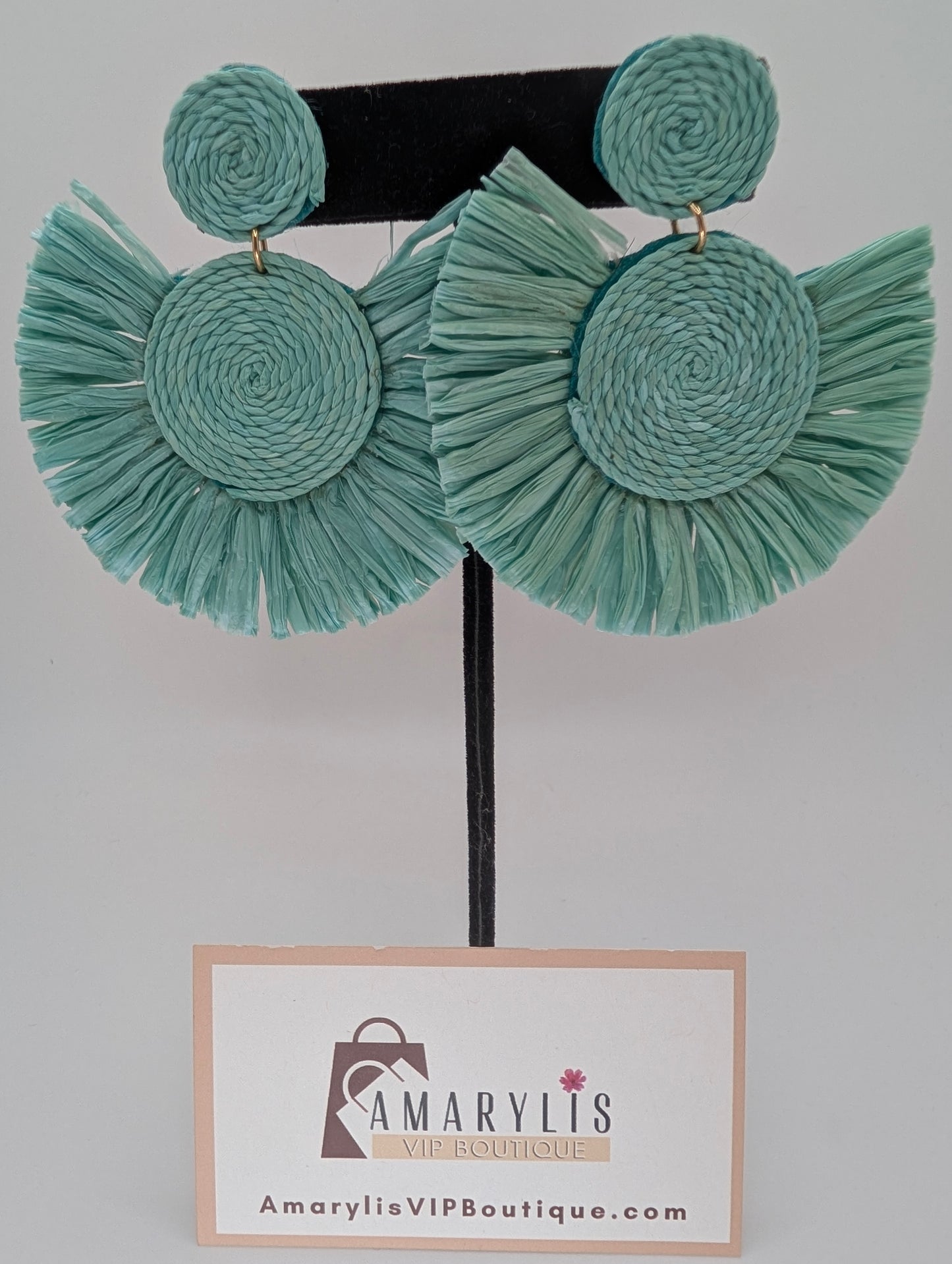 Teal raffia earrings on a hanger with Amarylis VIP Boutique label.