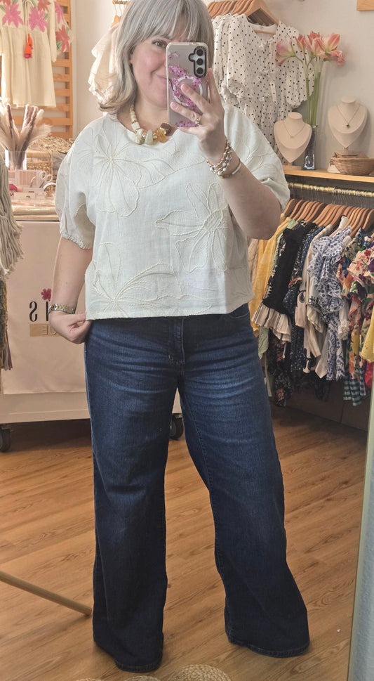 Beige linen-blend top with floral embroidery, featuring short dolman sleeves with elastic cuffs and a soft inner lining