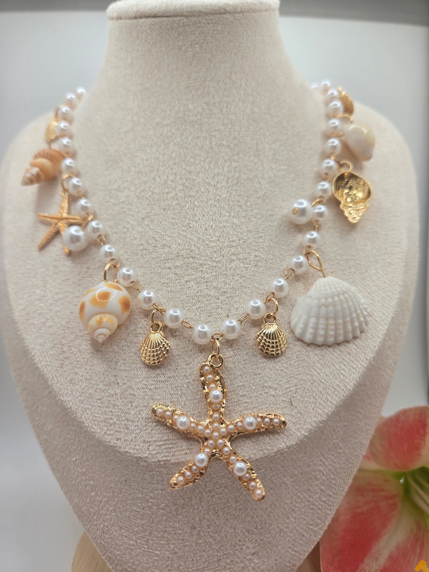 Pearl beaded necklace featuring shell charms, gold scallop accents, and a pearl embellished starfish pendant with an adjustable extender chain.