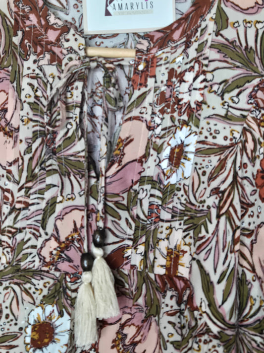 Soft and feminine peasant-style blouse featuring a delicate floral print, 3/4 length puff sleeves, and a tassel-tie neckline. Designed for effortless bohemian