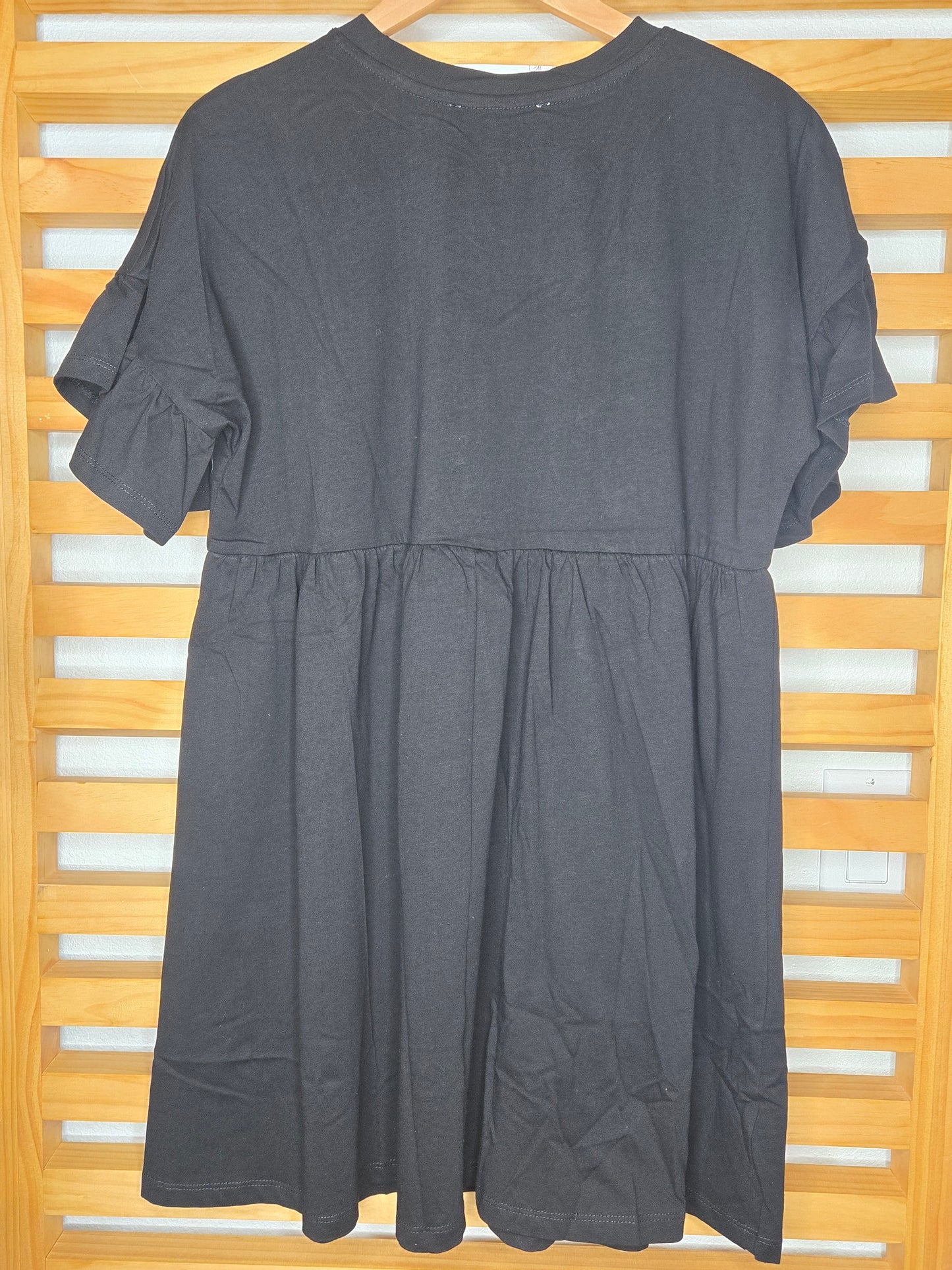 Short black cotton dress with round neckline, ruffle sleeves, and ruffle hem detail