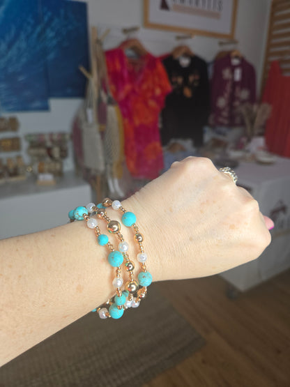 Turquoise stone, metallic, and pearl beaded bracelet set with layered design and textured detailing.