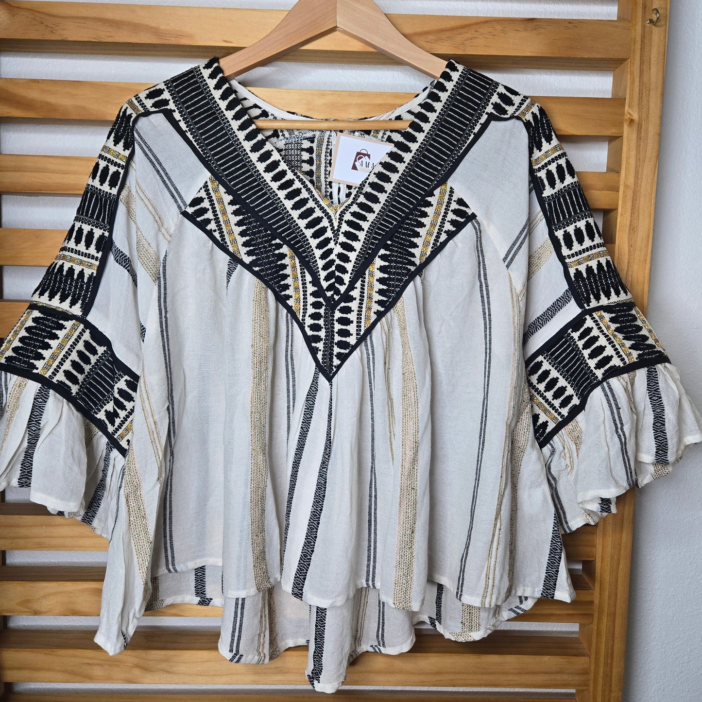V-neck blouse with black embroidery details, flutter sleeves, and vertical stitched accents for a flattering silhouette.