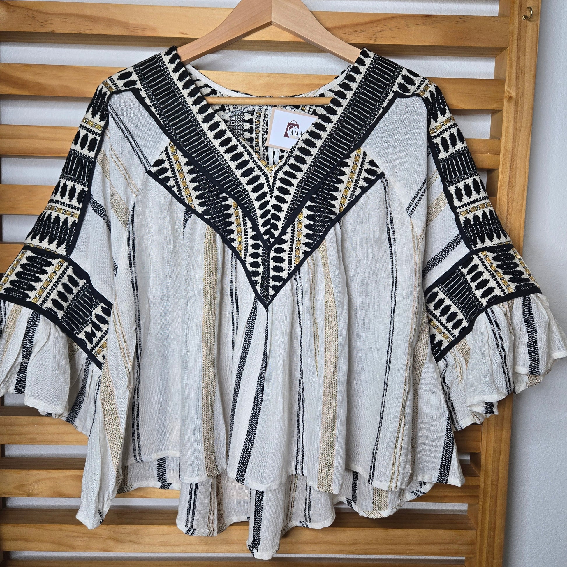 V-neck blouse with black embroidery details, flutter sleeves, and vertical stitched accents for a flattering silhouette.