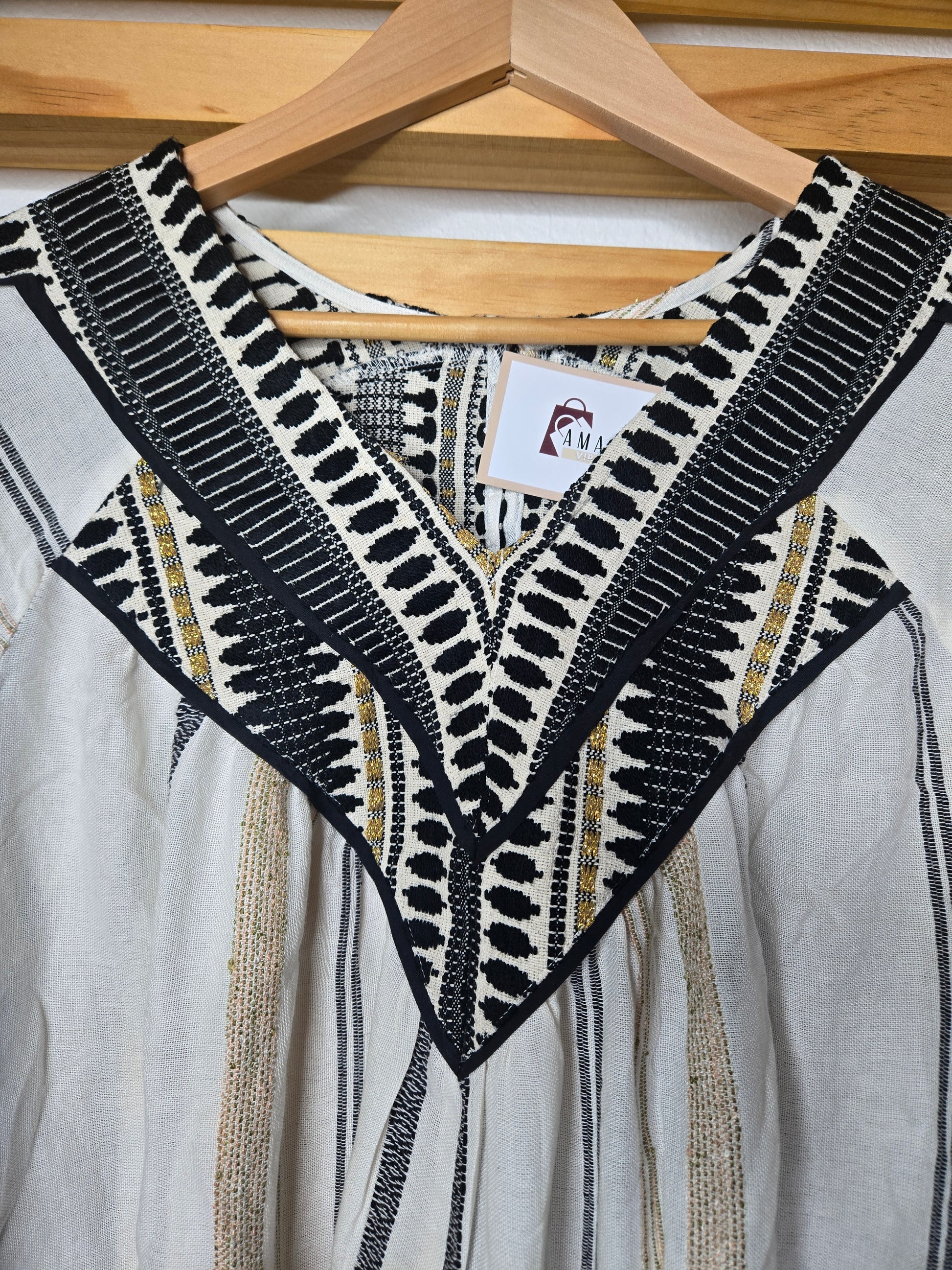 V-neck blouse with black embroidery details, flutter sleeves, and vertical stitched accents for a flattering silhouette.