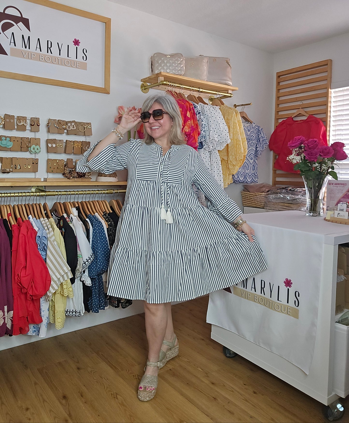 Navy striped cotton babydoll dress with bell sleeves, tassel tie neckline, relaxed fit silhouette, and functional side pockets.