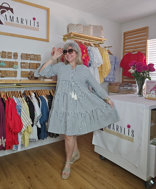 Navy striped cotton babydoll dress with bell sleeves, tassel tie neckline, relaxed fit silhouette, and functional side pockets.