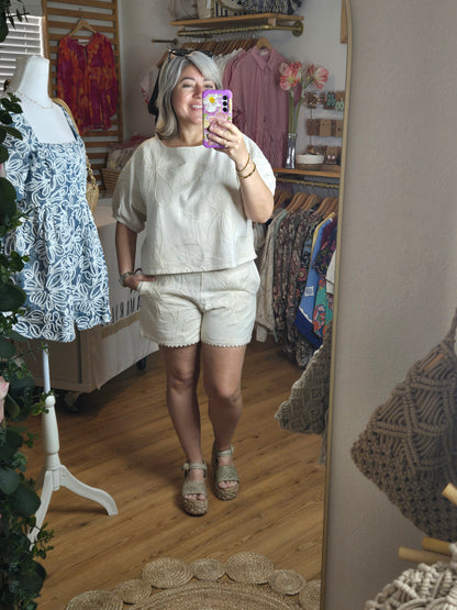 Beige embroidered shorts featuring delicate floral embroidery, crochet lace trim, side pockets, and a comfortable elastic waistband. Styled with the matching embroidered top, sold separately.