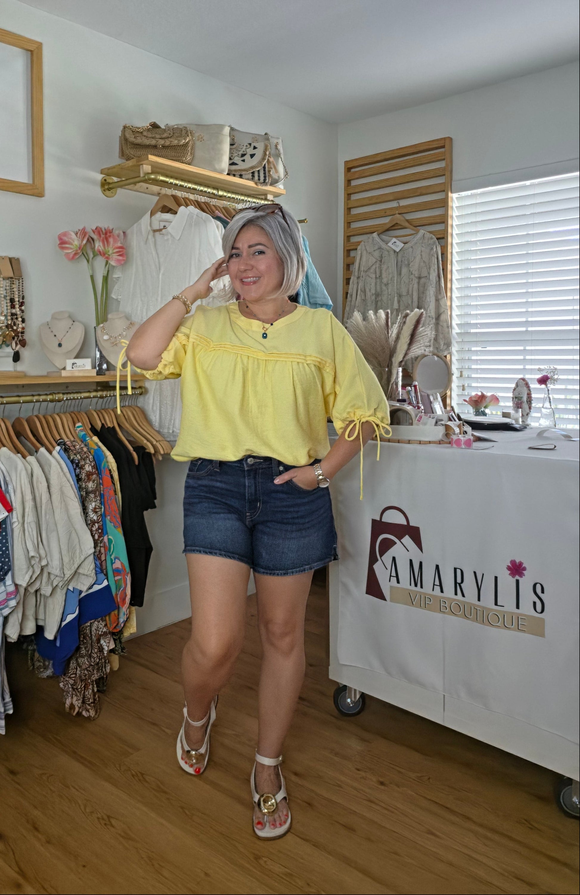 A yellow women's blouse with a round neckline, pleated details, short sleeves, and adjustable tie cuffs.