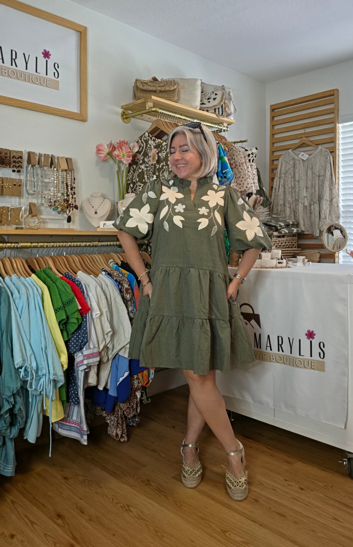 Olive boho dress with oversized floral embroidery, puff sleeves, tiered skirt, split neckline, and side pockets.
