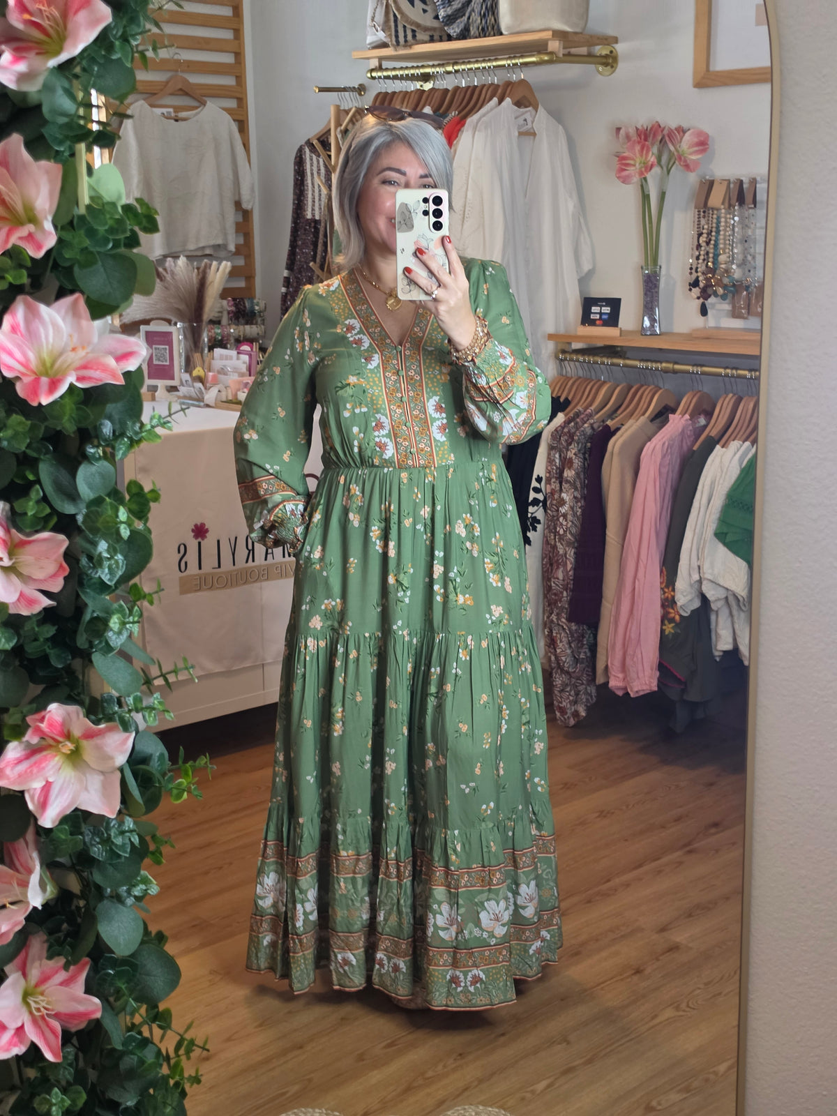 Floral print maxi dress featuring a contrasting border print, split V-neckline, button-front bodice, elastic empire waist, long sleeves with smocked cuffs, and tiered skirt.