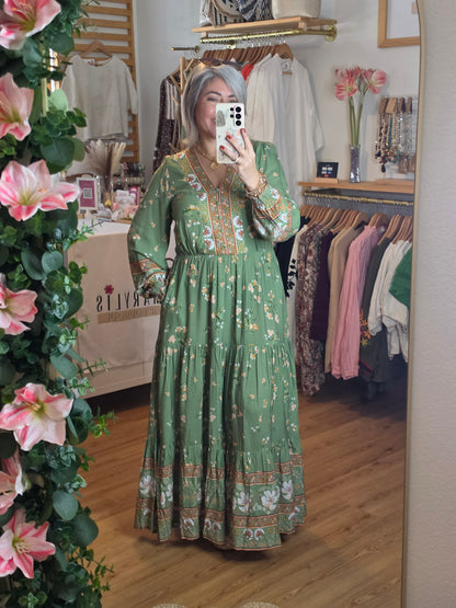 Floral print maxi dress featuring a contrasting border print, split V-neckline, button-front bodice, elastic empire waist, long sleeves with smocked cuffs, and tiered skirt.