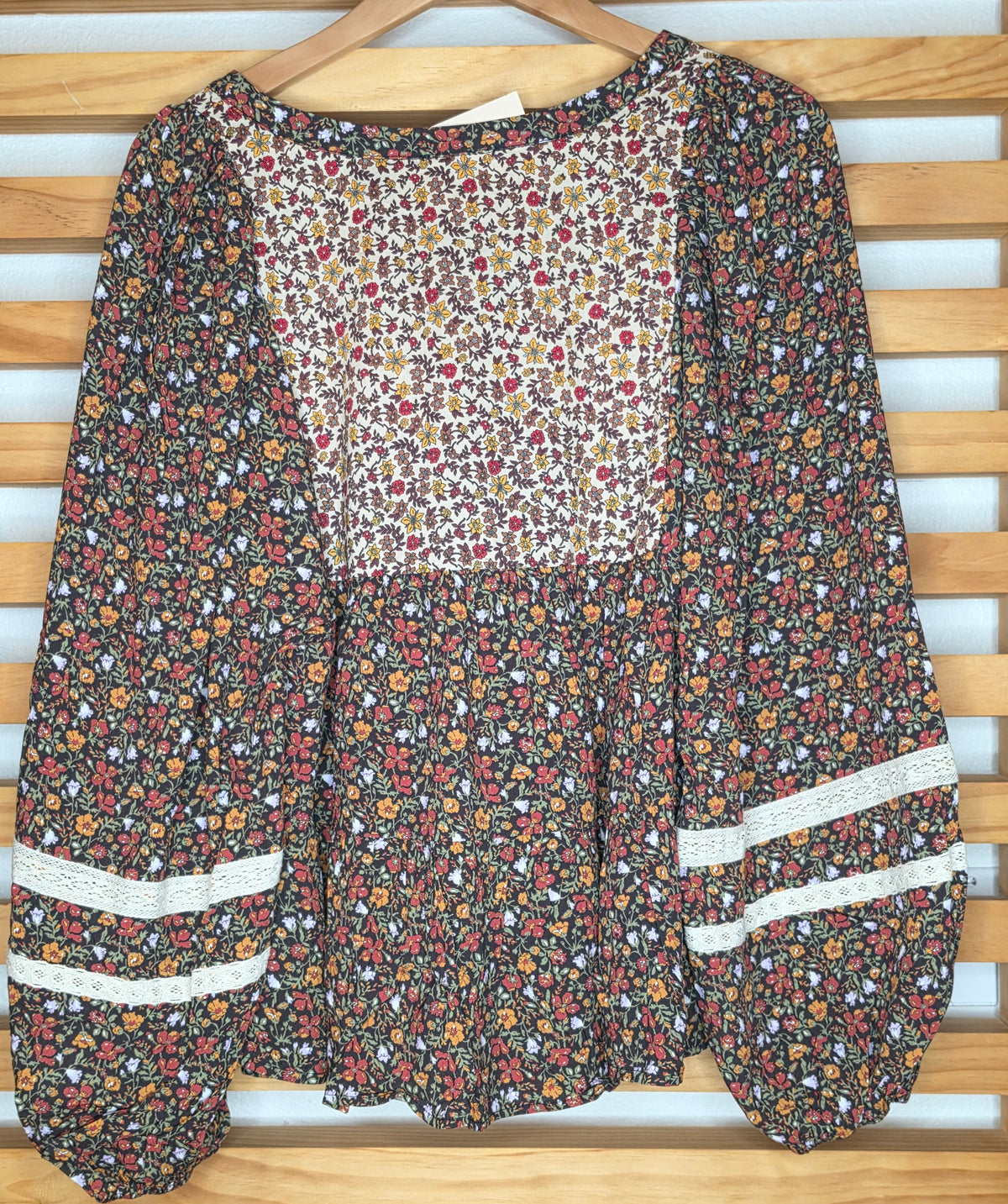 Women's floral print peplum blouse with lace accents on the front and sleeves and voluminous balloon sleeves in autumn colors