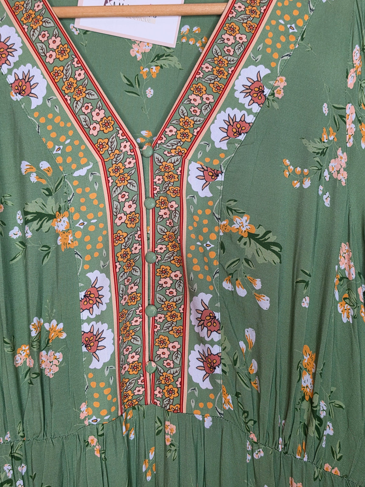 Floral print maxi dress featuring a contrasting border print, split V-neckline, button-front bodice, elastic empire waist, long sleeves with smocked cuffs, and tiered skirt.