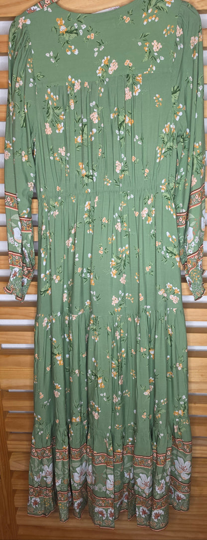 Floral print maxi dress featuring a contrasting border print, split V-neckline, button-front bodice, elastic empire waist, long sleeves with smocked cuffs, and tiered skirt.