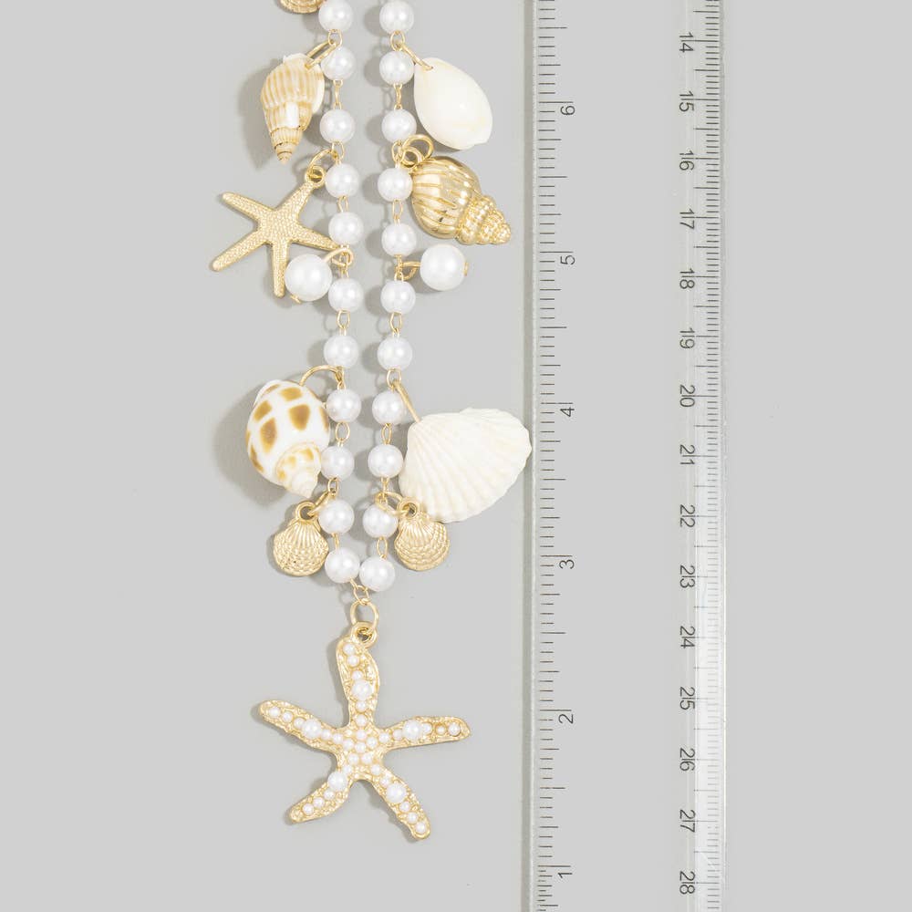Pearl beaded necklace featuring shell charms, gold scallop accents, and a pearl embellished starfish pendant with an adjustable extender chain.