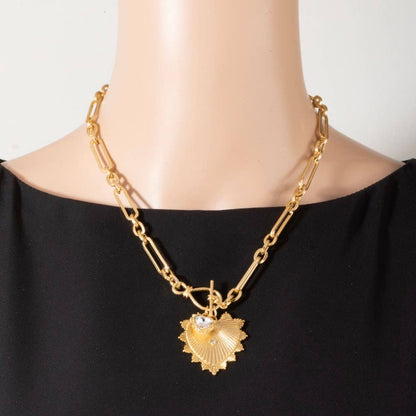 Gold chain necklace with a heart-shaped pendant on a mannequin wearing a black top.