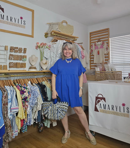 Short blue cotton dress with round neckline, drop shoulders, short ruffle sleeves, and ruffle hem in a relaxed fit design.