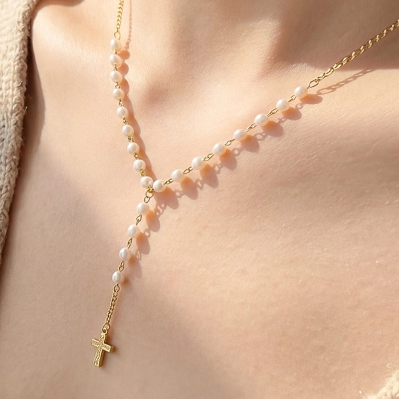 Elegante collar con cadena Y, detalles de perlas y delicado dije de cruz, ideal para complementar cualquier look.