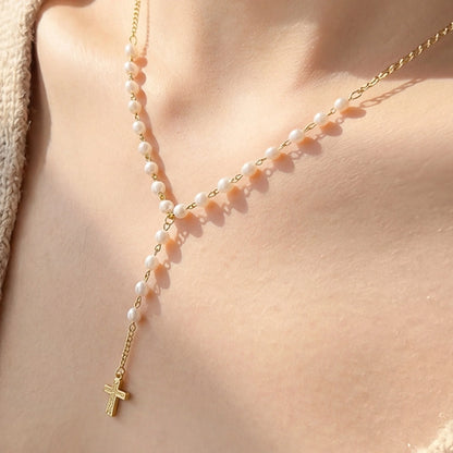 Elegante collar con cadena Y, detalles de perlas y delicado dije de cruz, ideal para complementar cualquier look.