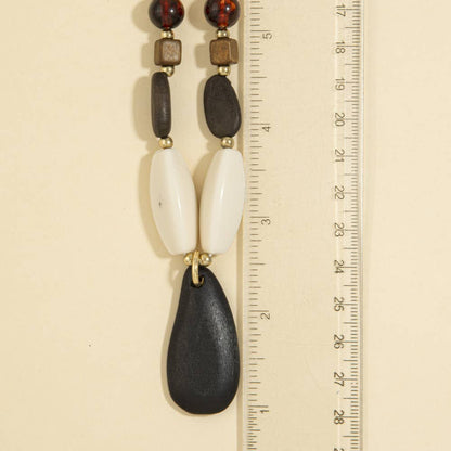 A timeless wood bead necklace with a graceful teardrop pendant, designed to bring natural beauty and effortless elegance to your wardrobe.