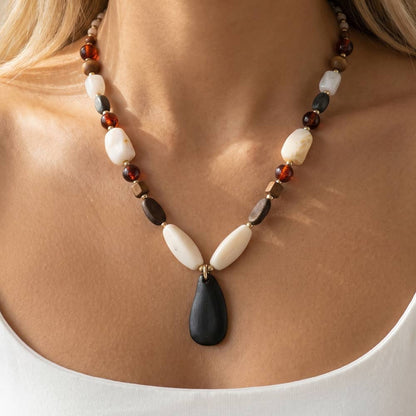 A timeless wood bead necklace with a graceful teardrop pendant, designed to bring natural beauty and effortless elegance to your wardrobe.