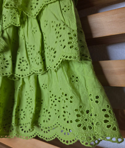 Women's eyelet shorts featuring a tiered ruffle design, elastic waistband, and adjustable tassel drawstring, available in green and white.