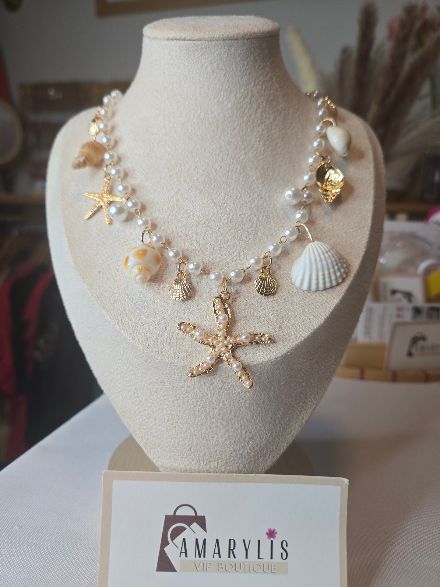Pearl beaded necklace featuring shell charms, gold scallop accents, and a pearl embellished starfish pendant with an adjustable extender chain.