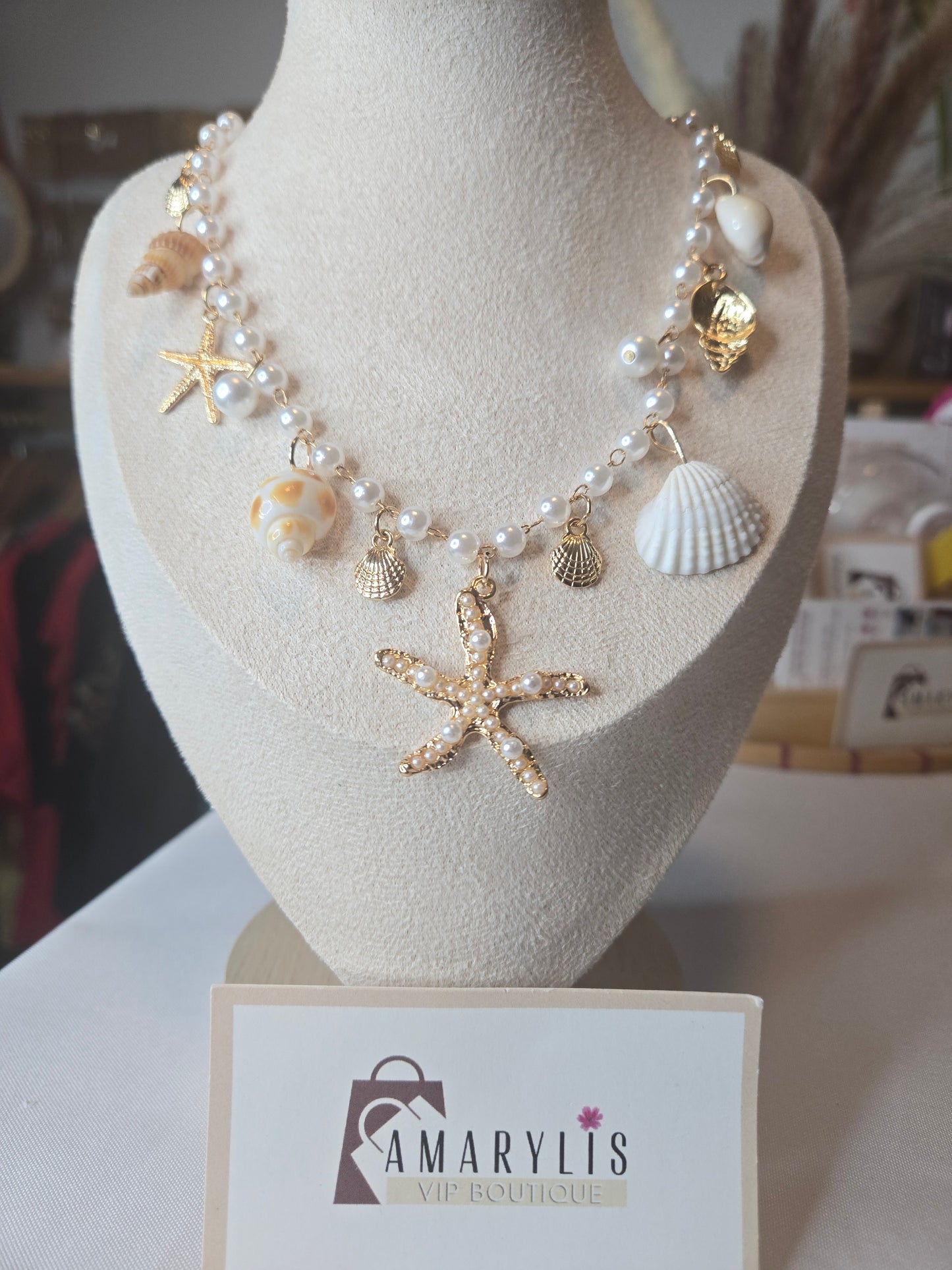 Pearl beaded necklace featuring shell charms, gold scallop accents, and a pearl embellished starfish pendant with an adjustable extender chain.