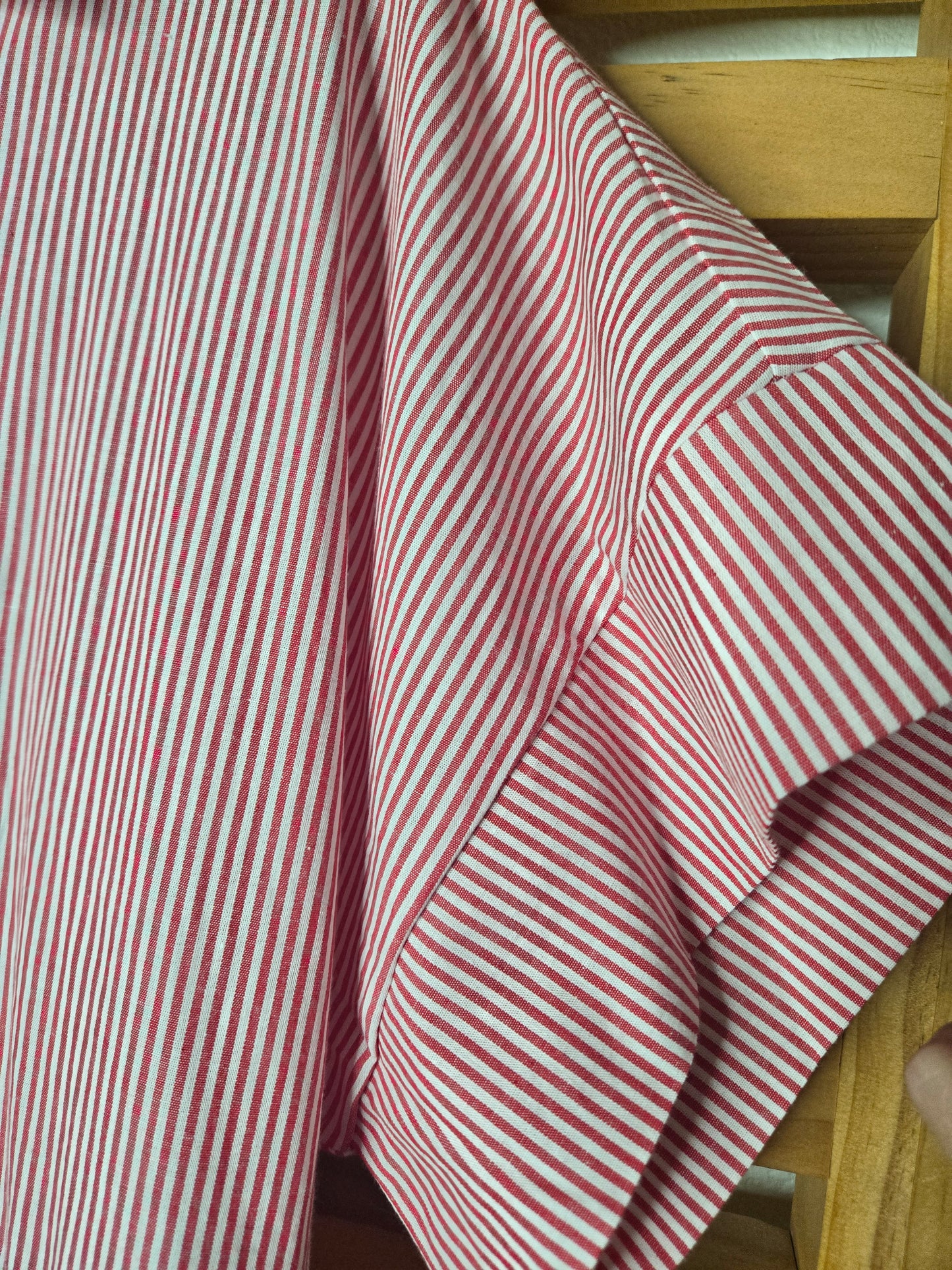 Red striped cotton dress with collared neckline, rolled short sleeves, button front detail, tiered skirt, ruffled hem, and adjustable tie waist.