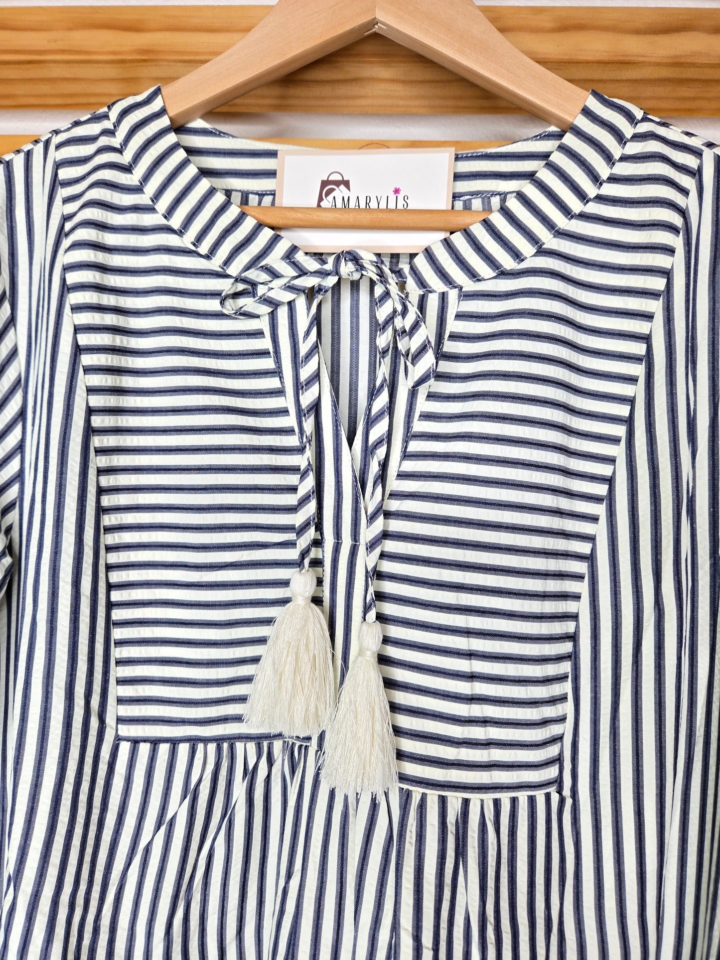 Navy striped cotton babydoll dress with bell sleeves, tassel tie neckline, relaxed fit silhouette, and functional side pockets.