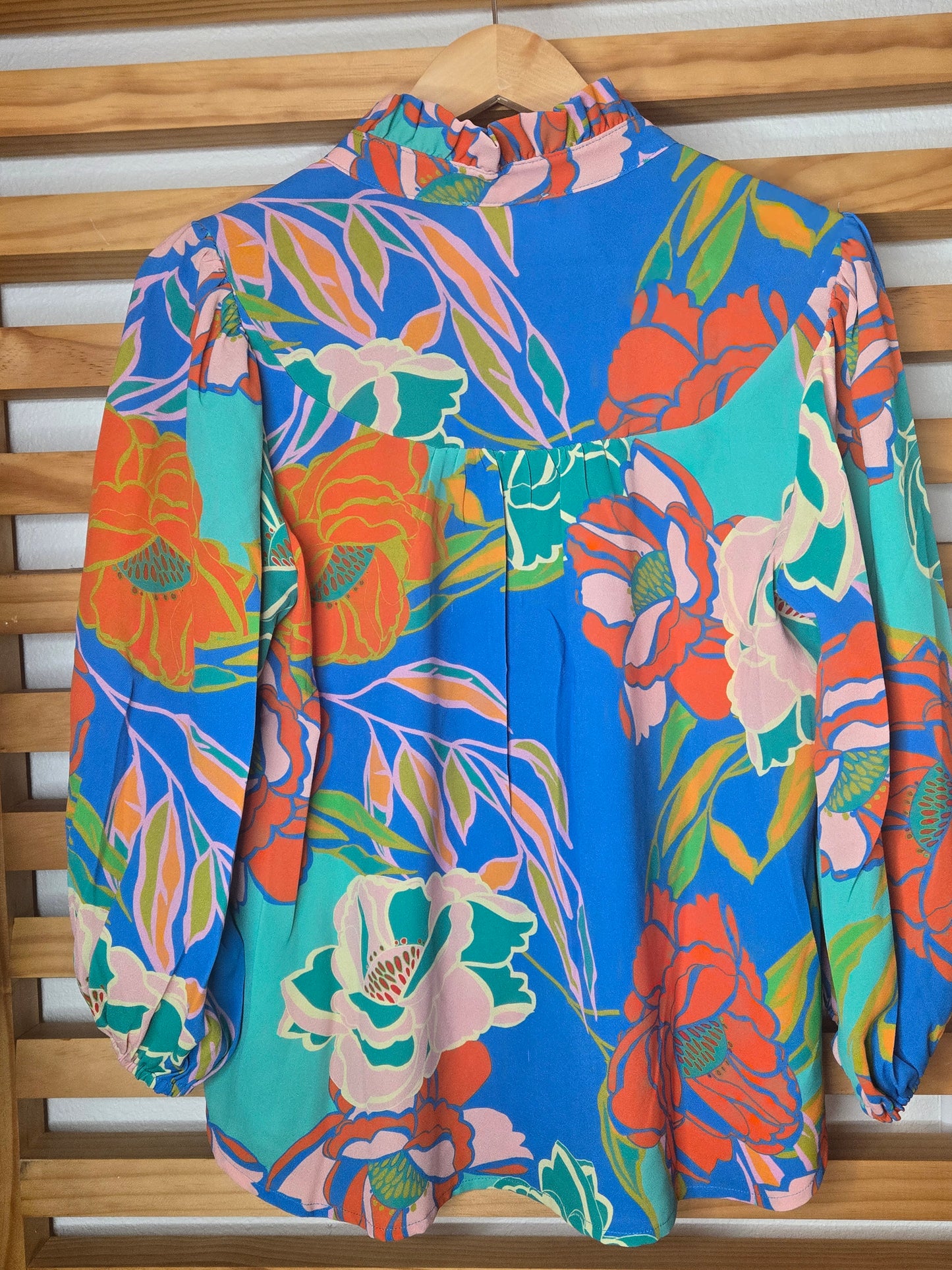 Floral printed blouse featuring 3/4 sleeves and a soft ruffled neckline detail.