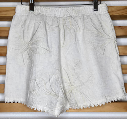 Beige embroidered shorts featuring delicate floral embroidery, crochet lace trim, side pockets, and a comfortable elastic waistband. Styled with the matching embroidered top, sold separately.