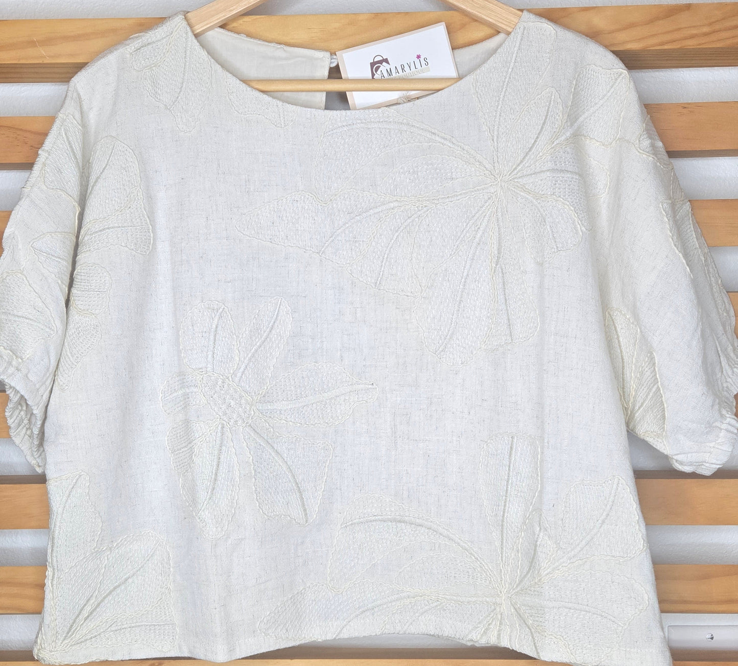 Beige linen-blend top with floral embroidery, featuring short dolman sleeves with elastic cuffs and a soft inner lining