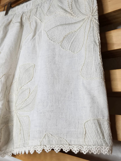 Beige embroidered shorts featuring delicate floral embroidery, crochet lace trim, side pockets, and a comfortable elastic waistband. Styled with the matching embroidered top, sold separately.