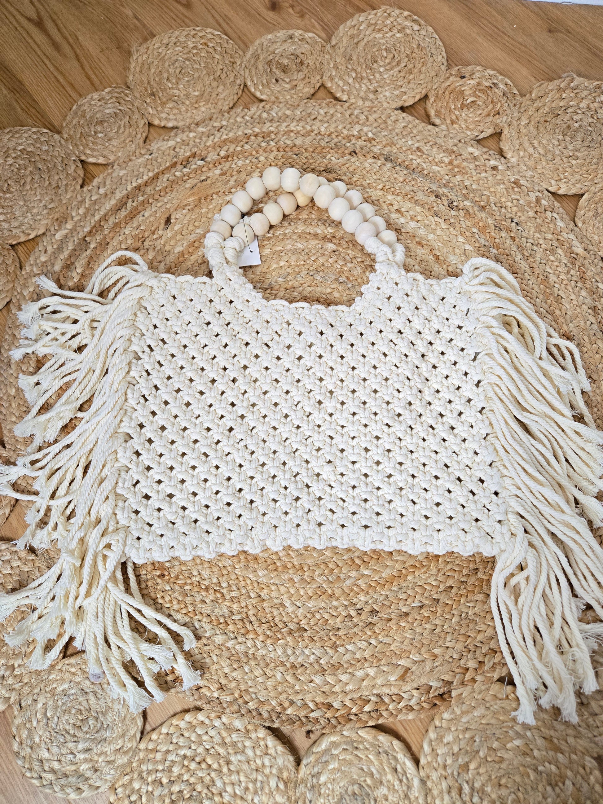 Large woven macrame tote bag with intricate knotted design, long fringe trim, and braided shoulder strap.