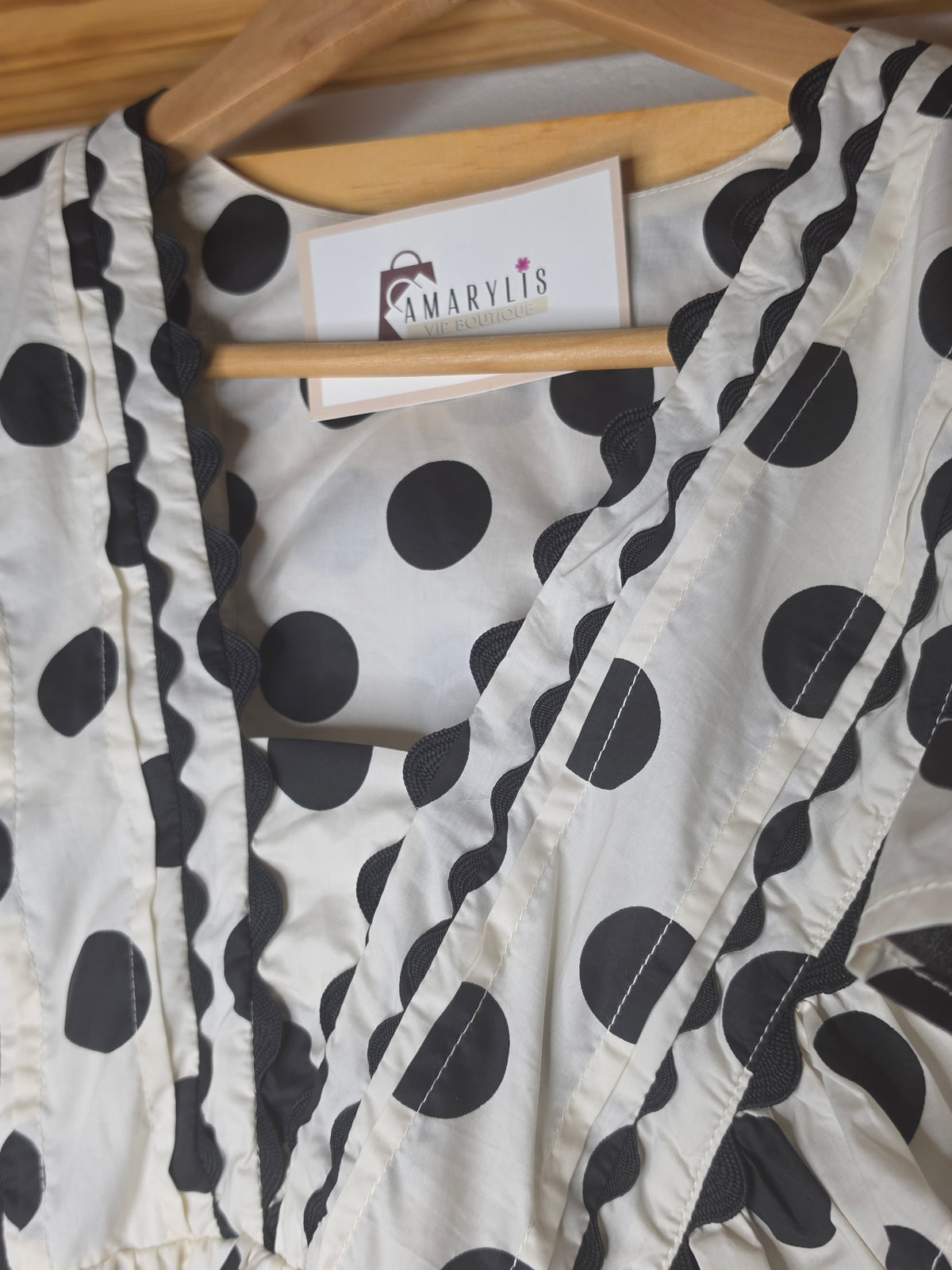 Black and white polka dot babydoll blouse with ruffle details, fitted bust, relaxed lower silhouette, and side zipper.