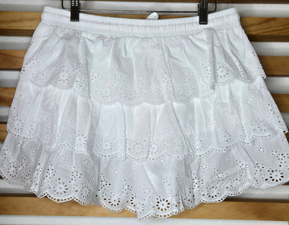 Women's eyelet shorts featuring a tiered ruffle design, elastic waistband, and adjustable tassel drawstring, available in green and white.