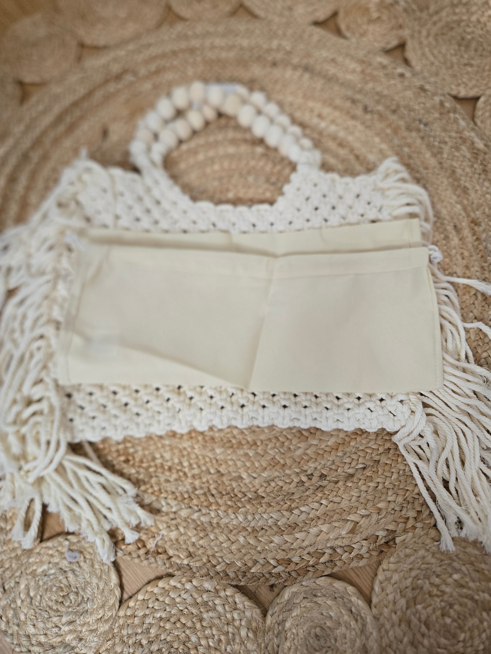 Large woven macrame tote bag with intricate knotted design, long fringe trim, and braided shoulder strap.
