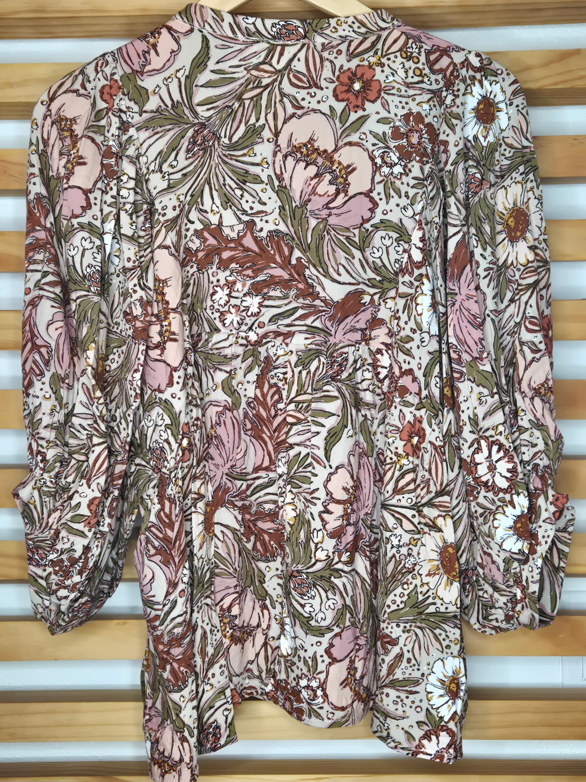 Soft and feminine peasant-style blouse featuring a delicate floral print, 3/4 length puff sleeves, and a tassel-tie neckline. Designed for effortless bohemian