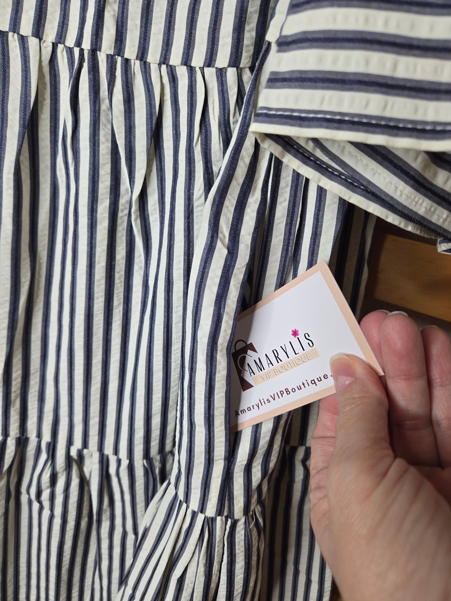 Navy striped cotton babydoll dress with bell sleeves, tassel tie neckline, relaxed fit silhouette, and functional side pockets.