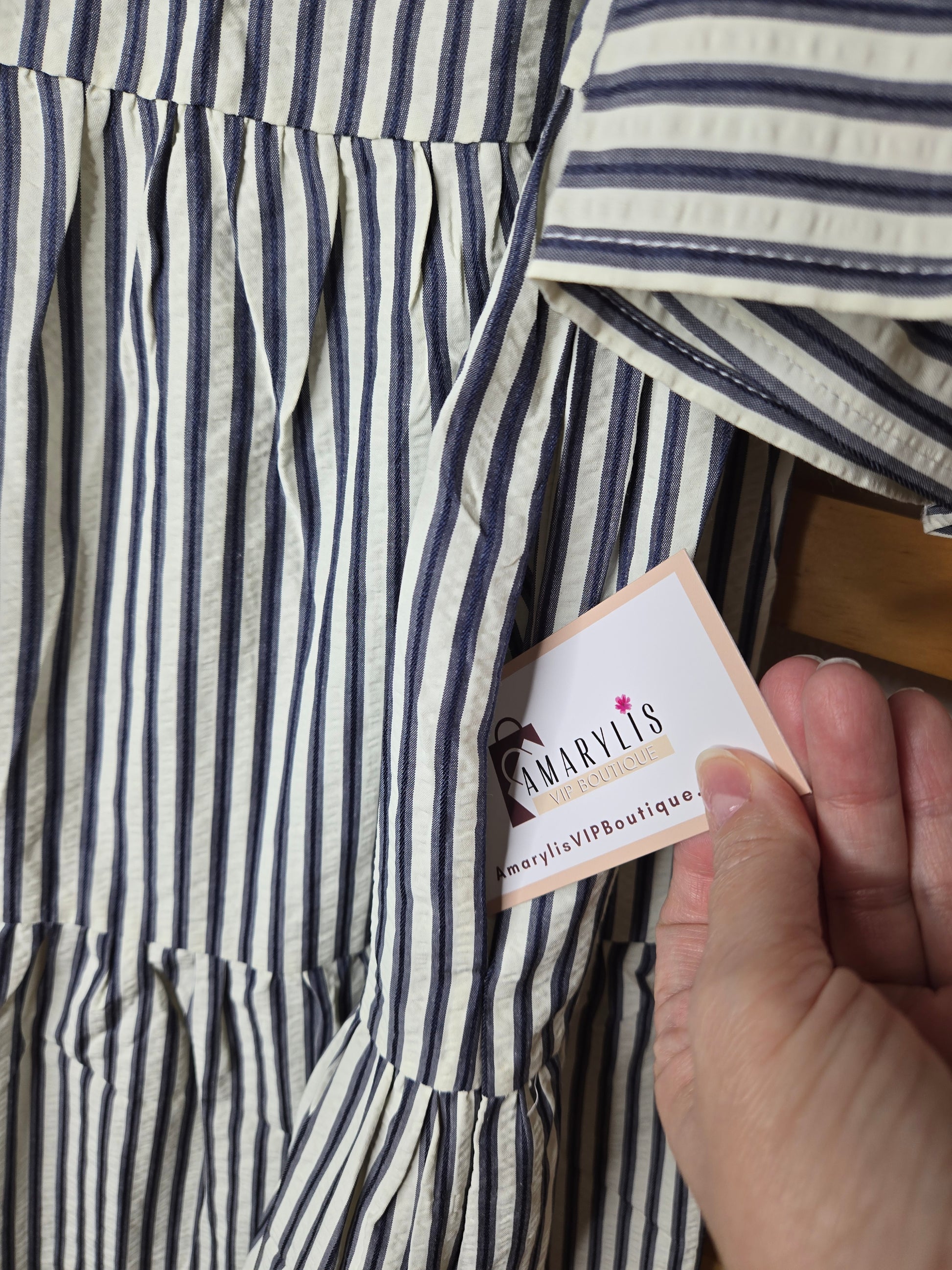 Navy striped cotton babydoll dress with bell sleeves, tassel tie neckline, relaxed fit silhouette, and functional side pockets.