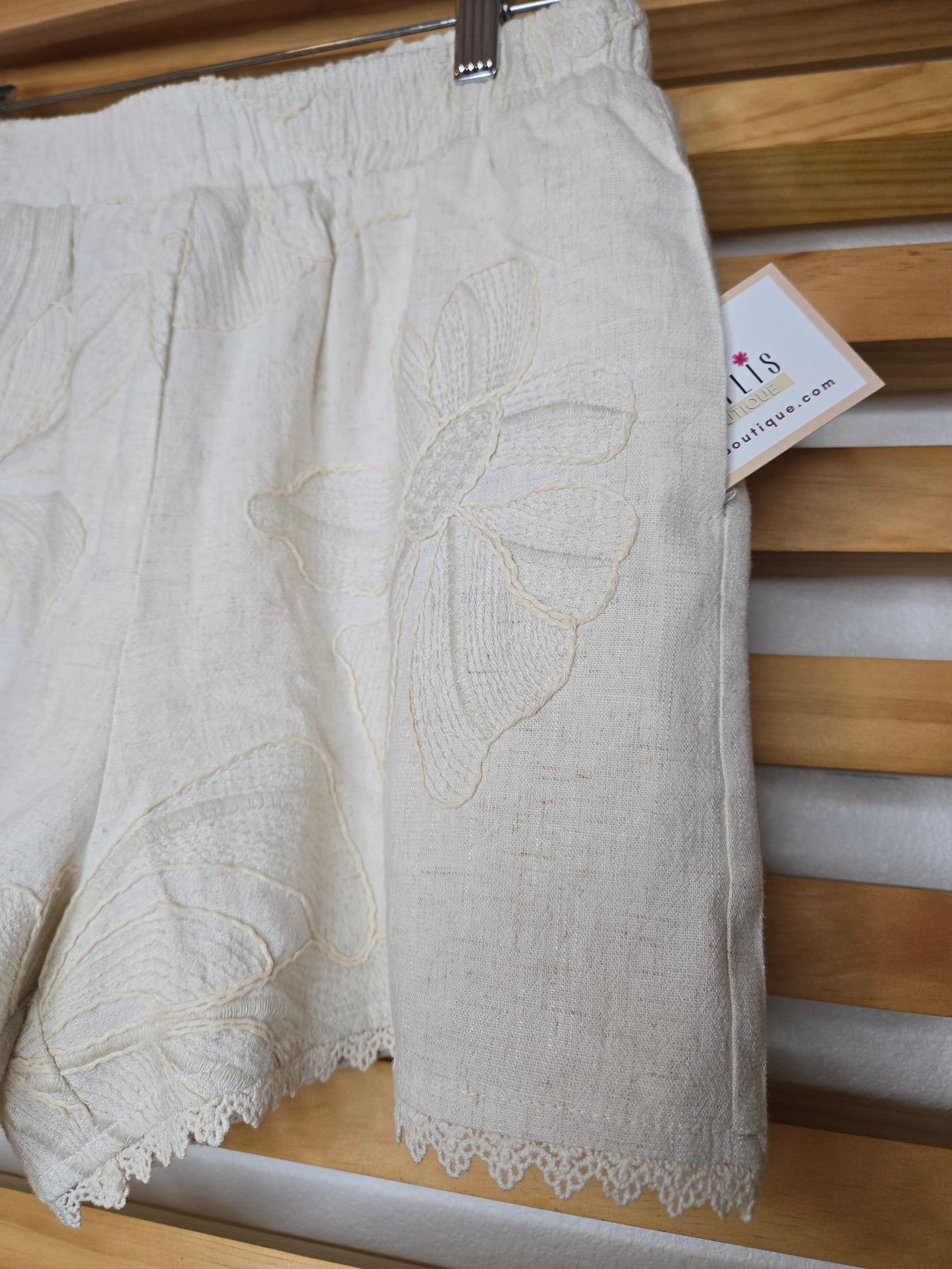 Beige embroidered shorts featuring delicate floral embroidery, crochet lace trim, side pockets, and a comfortable elastic waistband. Styled with the matching embroidered top, sold separately.