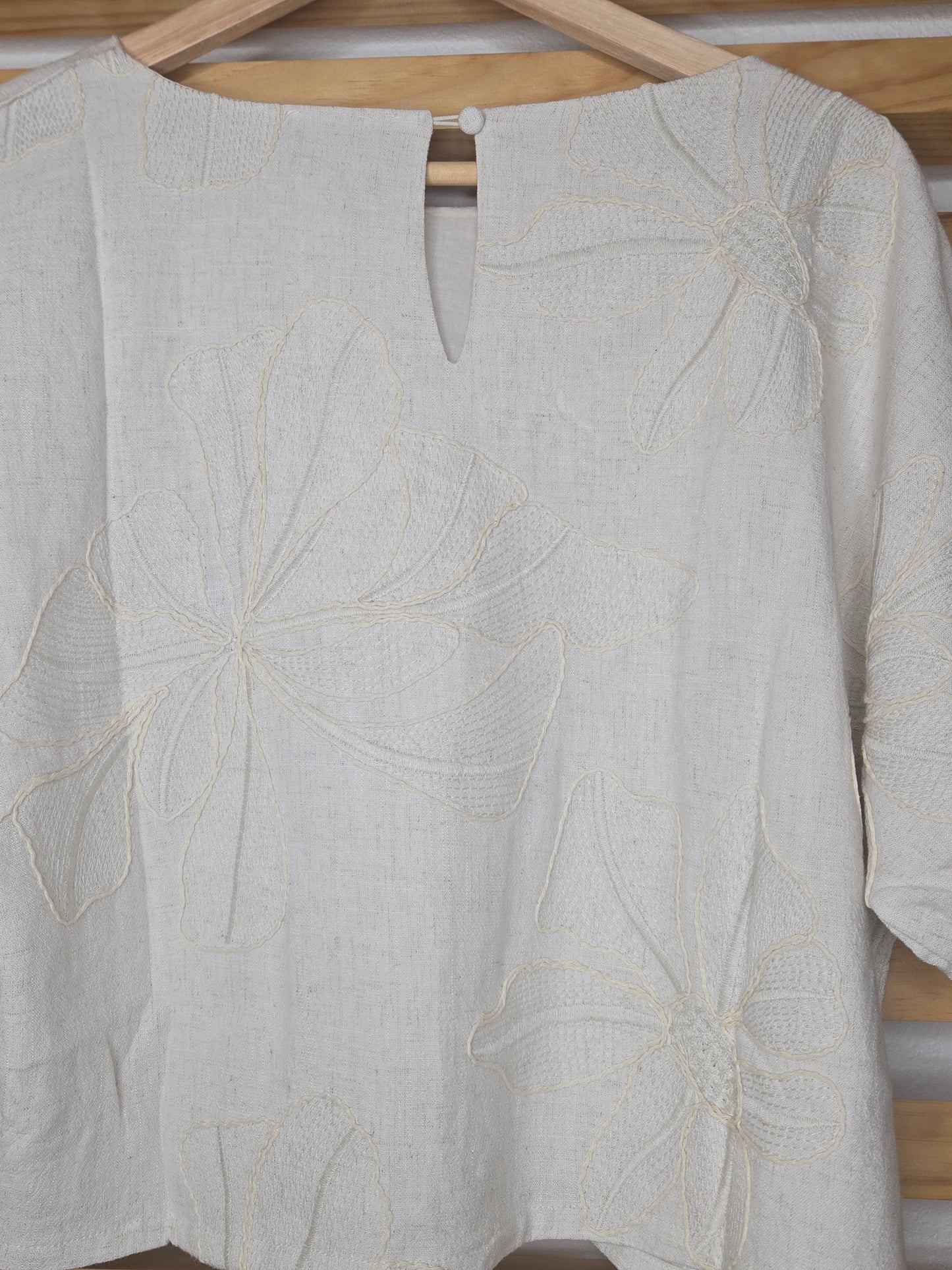 Beige linen-blend top with floral embroidery, featuring short dolman sleeves with elastic cuffs and a soft inner lining