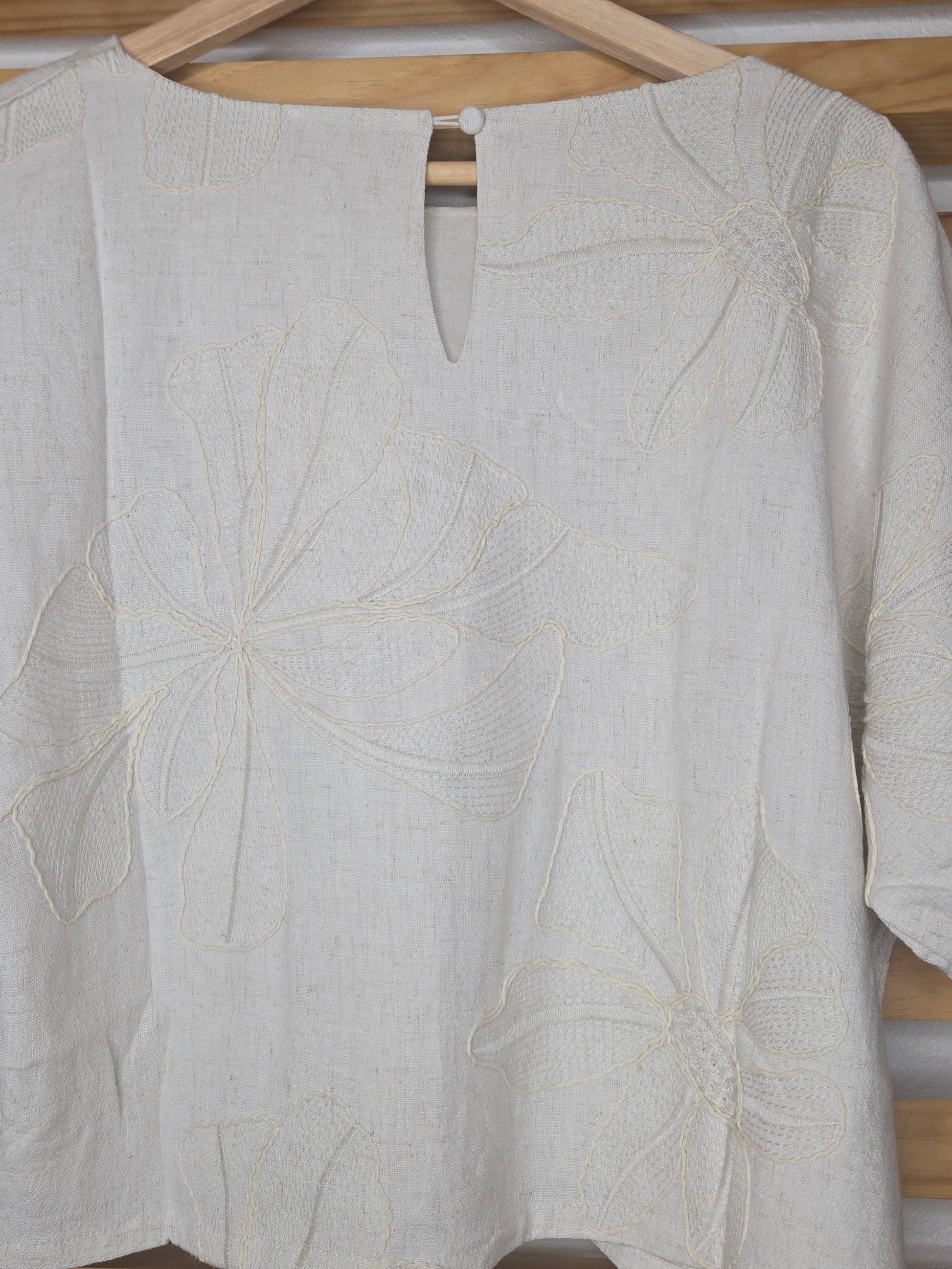Beige linen-blend top with floral embroidery, featuring short dolman sleeves with elastic cuffs and a soft inner lining
