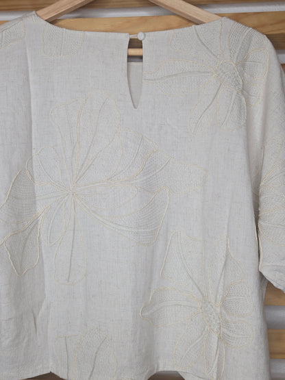 Beige linen-blend top with floral embroidery, featuring short dolman sleeves with elastic cuffs and a soft inner lining