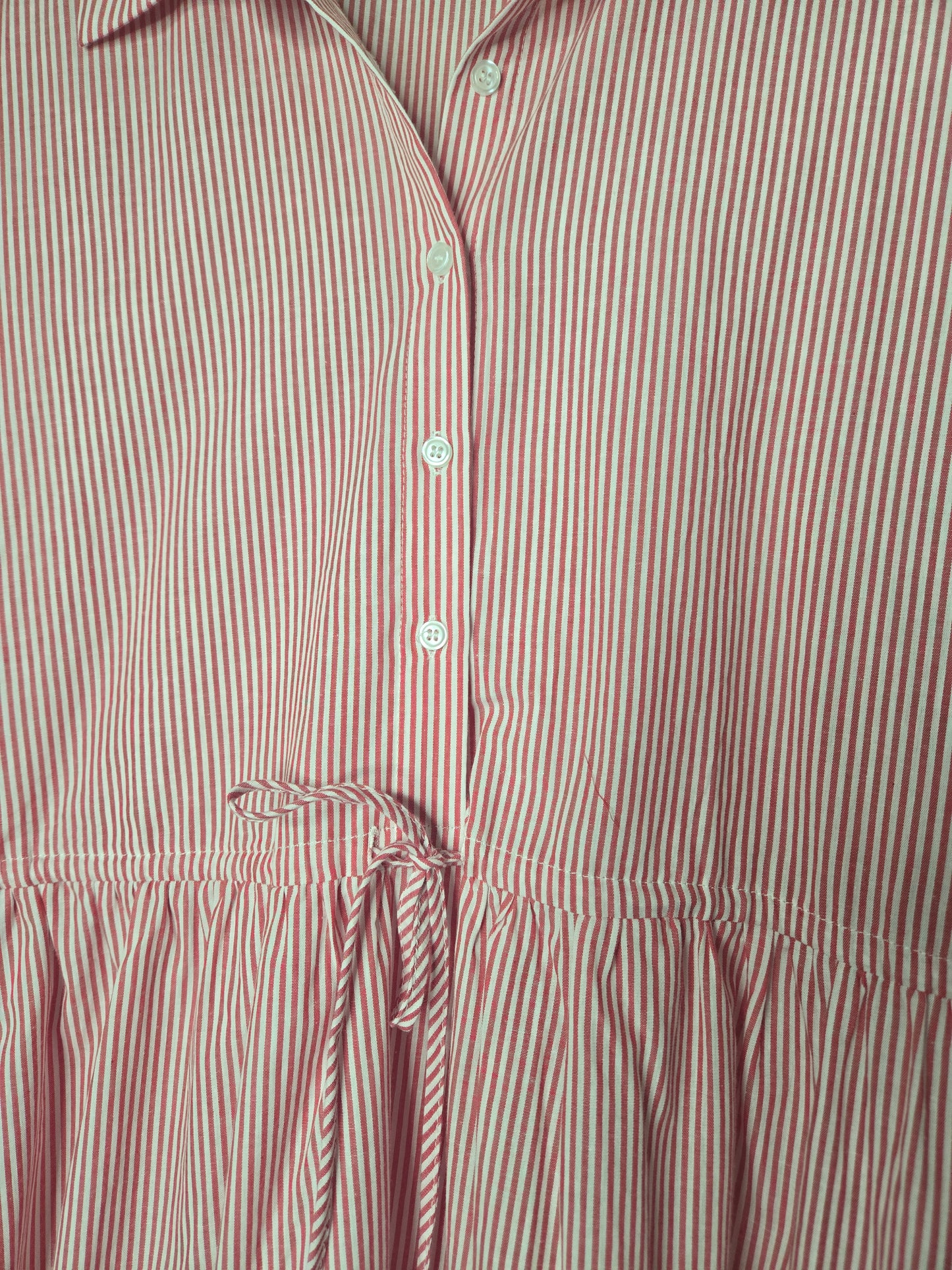 Red striped cotton dress with collared neckline, rolled short sleeves, button front detail, tiered skirt, ruffled hem, and adjustable tie waist.