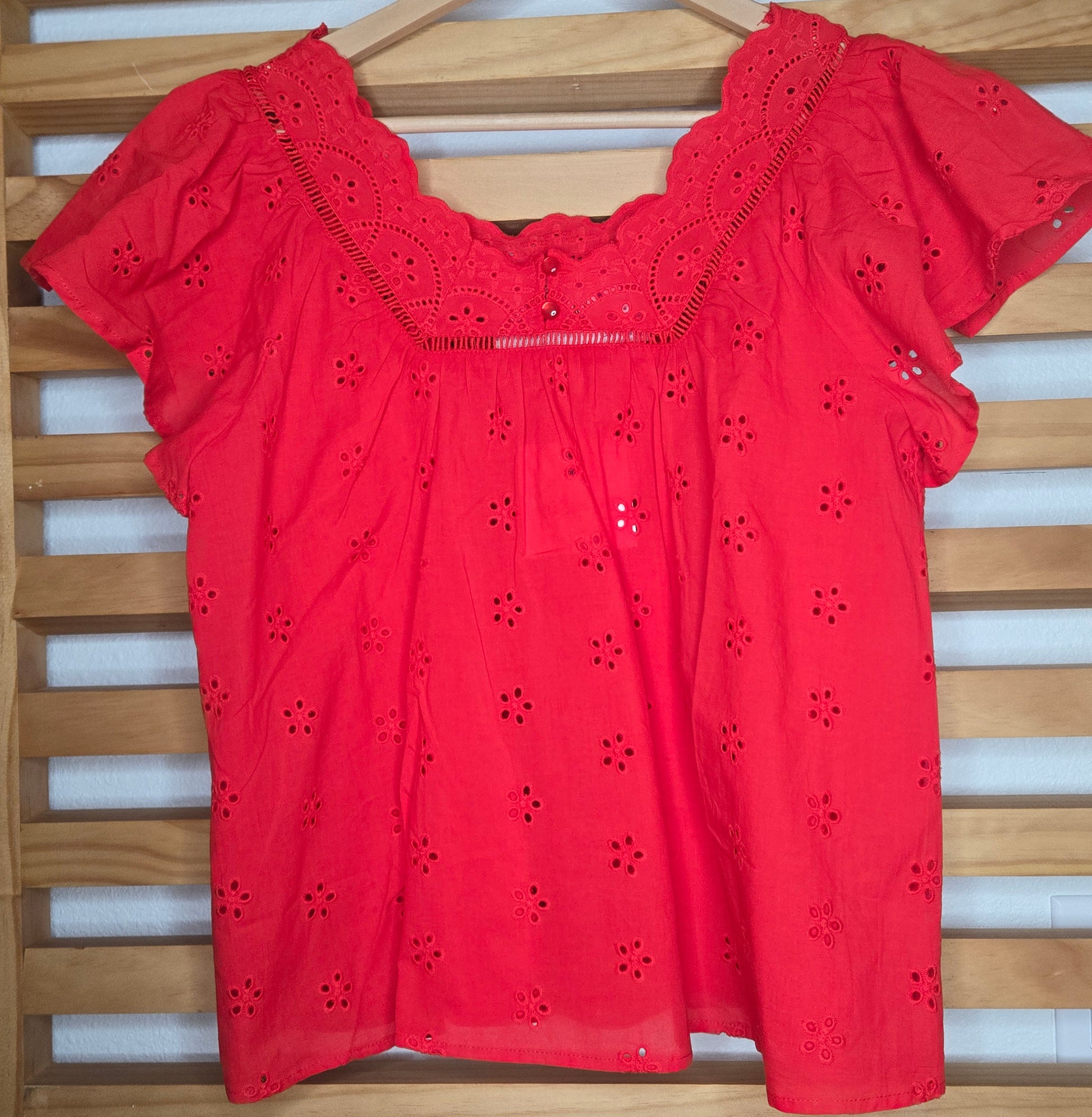 Women's red eyelet blouse with floral embroidery and short flutter sleeves.