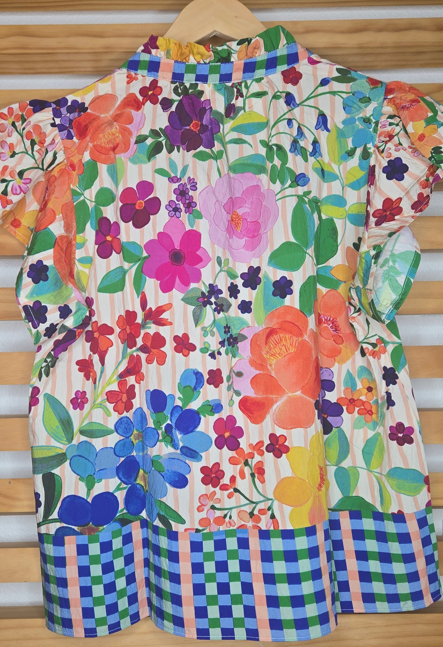 Lightweight blouse featuring soft flutter sleeves and a delicate floral border print. Designed with a feminine ruffled V-neckline, perfect for an effortless boho-inspired look.