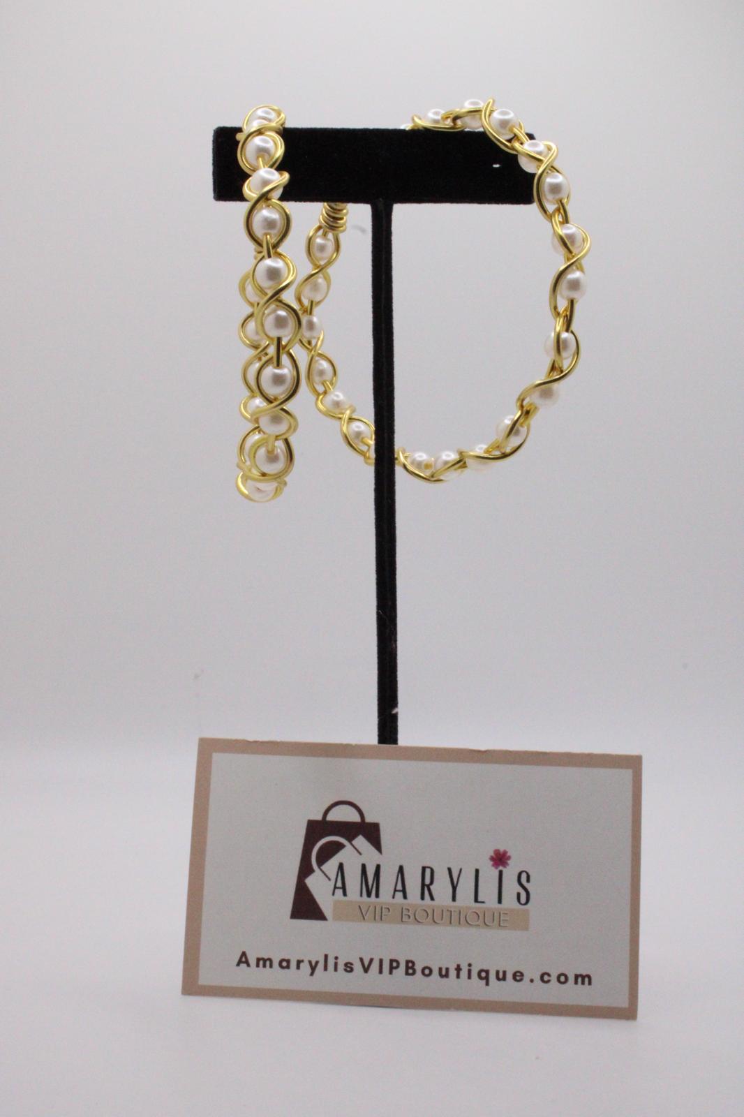 A gold-tone jewelry set with white faux pearls, including a bracelet and matching earrings, displayed on a black stand with a branded card below on a light gray background.